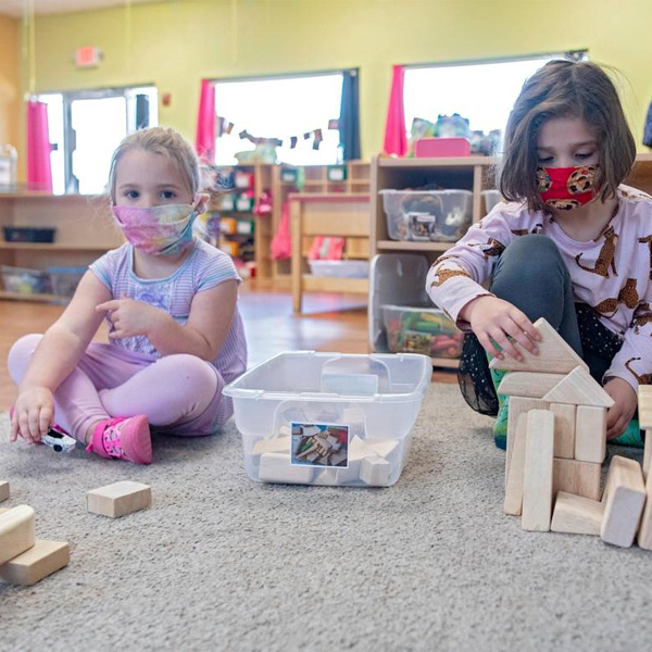 Students playing with blocks wearing masks