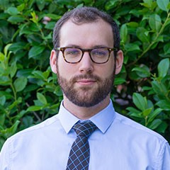 Professional headshot of Pinnacle Award Winner Alex M.,a young man with glasses and a neat beard.