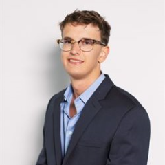 A professional headshot of Pinnacle Award Winner Peyton C. He has short brown hair and glasses, and is smiling at the camera.