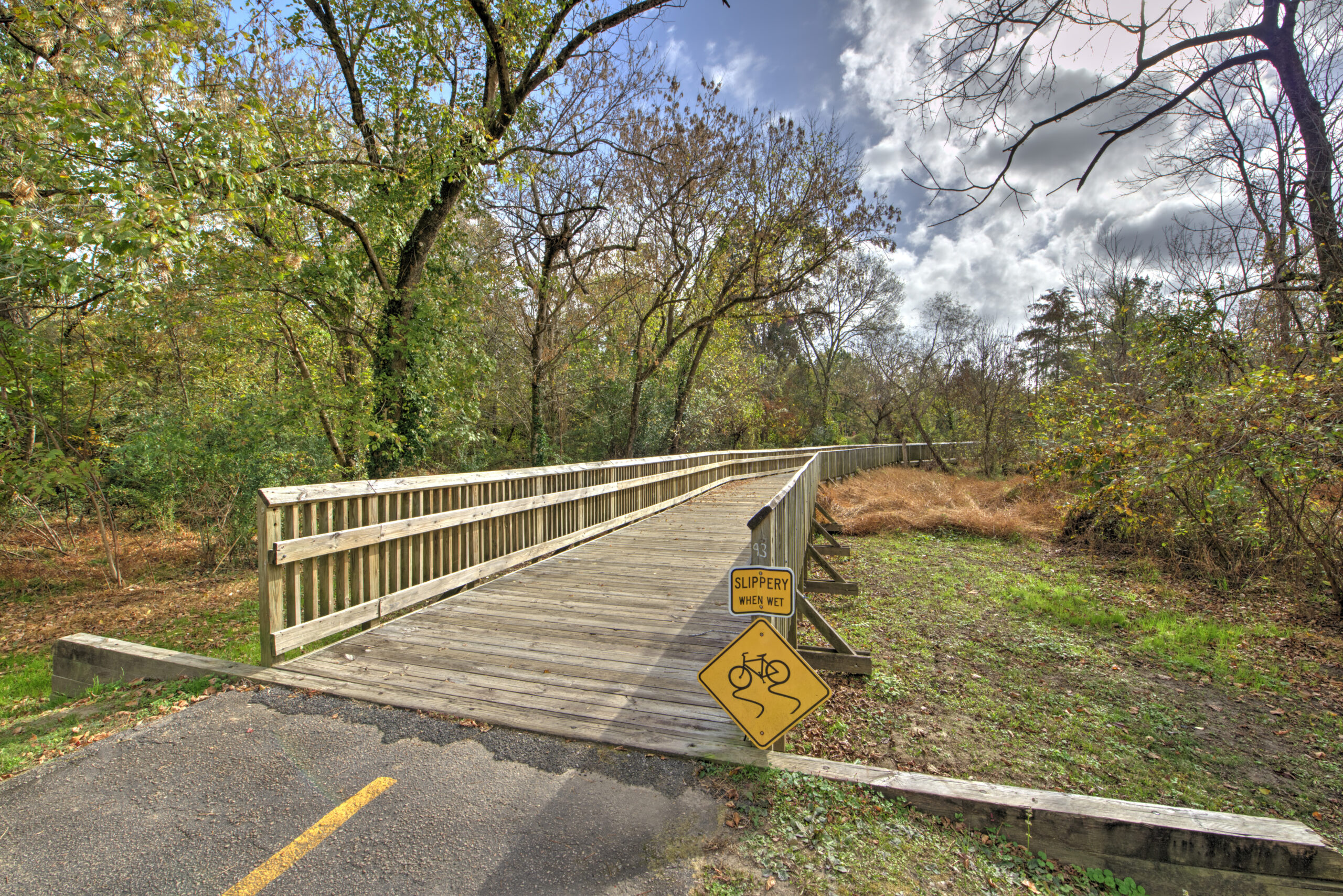 A walkway with signage for the North Carolina Wetlands Park at Walnut Creek